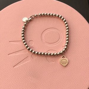 Tiffany & Co rose gold return to Tiffany heart tag on a silver beaded bracelet.